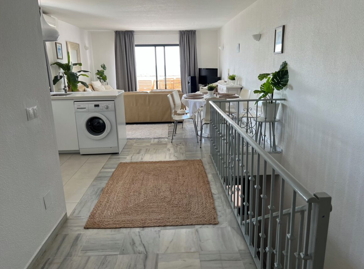 Un appartamento moderno con cucina, zona pranzo e soggiorno. Dispone di lavatrice, tavolo da pranzo con sedie, divano e televisione.