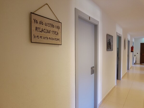 A hallway with a sign on the wall, a door, and a fire extinguisher on the wall.