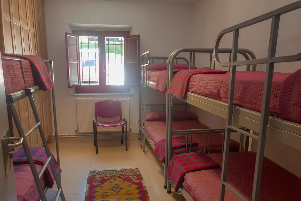 Un dormitorio con literas, un radiador, una ventana y una silla.