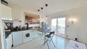 Una cocina moderna con comedor, lavadora y un amplio ventanal con vistas a la ciudad.