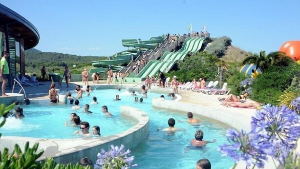 Un área de piscina con múltiples toboganes y sillones de descanso.