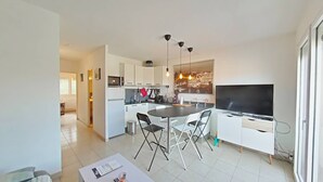 Una cocina moderna con armarios blancos, una mesa de comedor con sillas y un televisor de pantalla plana.