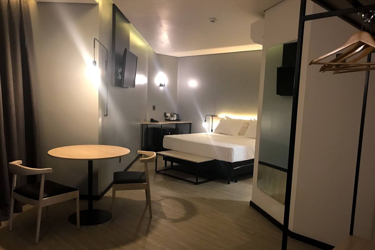 Een hotelkamer met een bed, een bureau, een stoel, een tafel en een kledingkast.