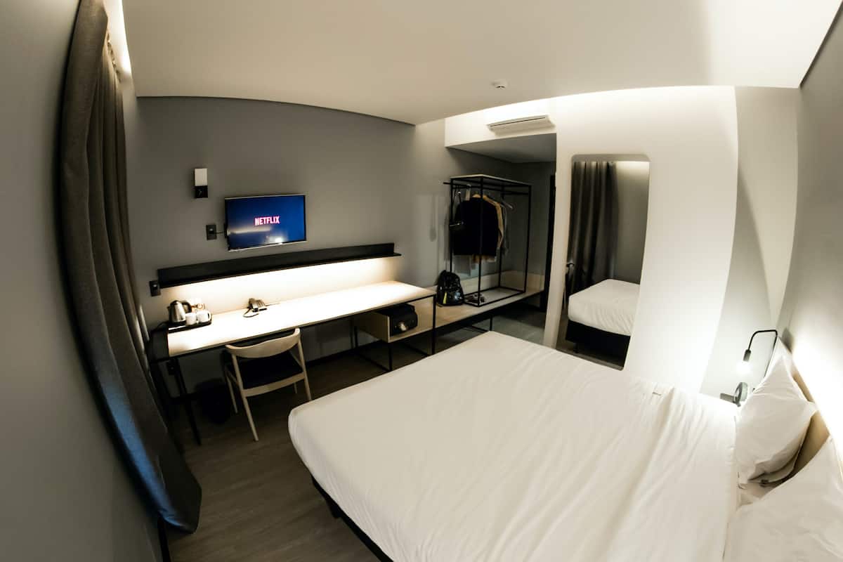 Een hotelkamer met een bed, een bureau, een stoel, een televisie en een kledingkast.