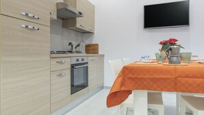 Une cuisine moderne avec des meubles en bois, un four encastré et un coin repas avec une table dressée pour deux personnes.