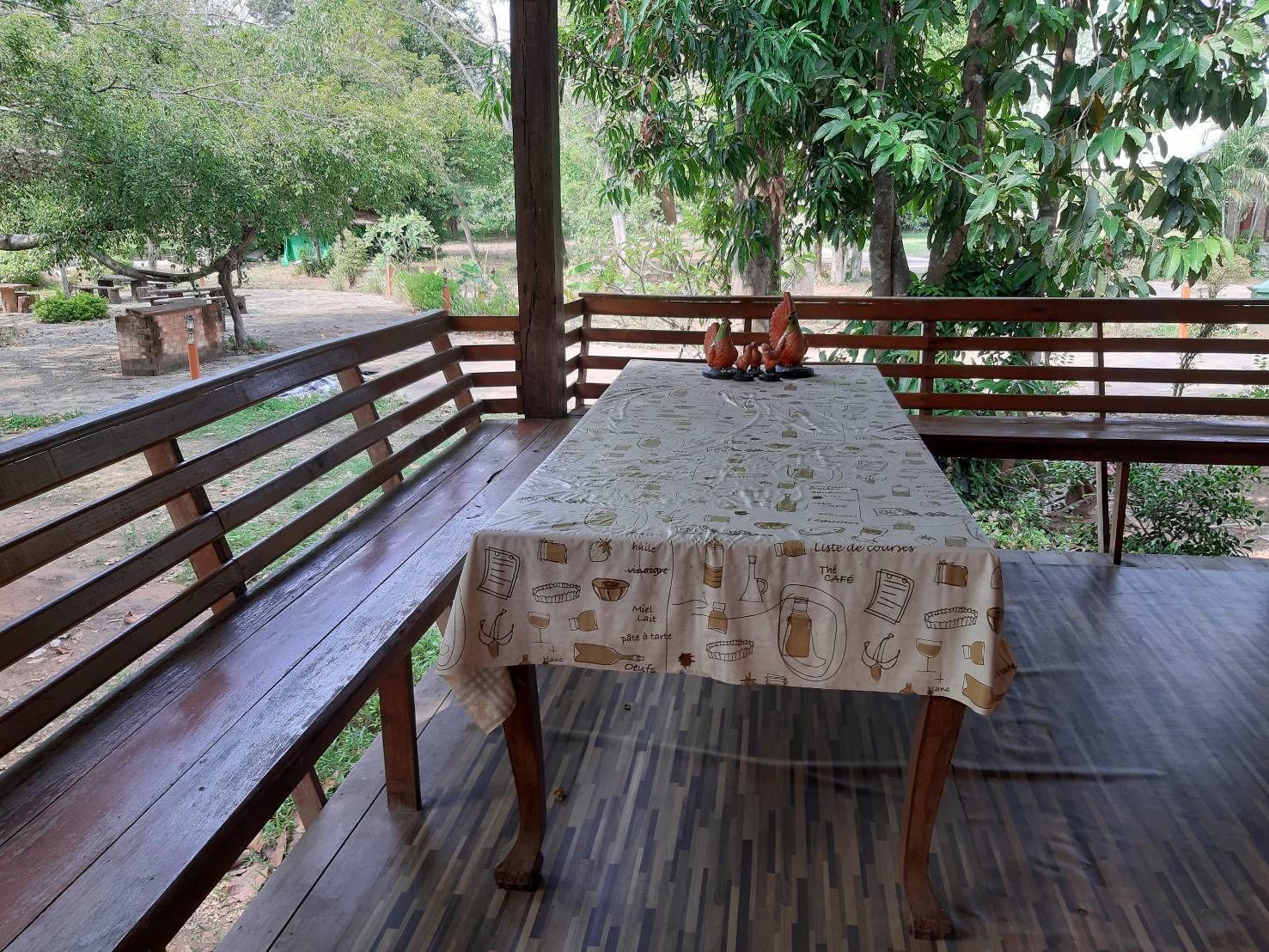 A wooden deck with a table covered by a tablecloth featuring food and drink illustrations.