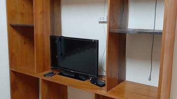 Un mueble de madera para televisor con televisor de pantalla plana, controles remotos y cable de alimentación.