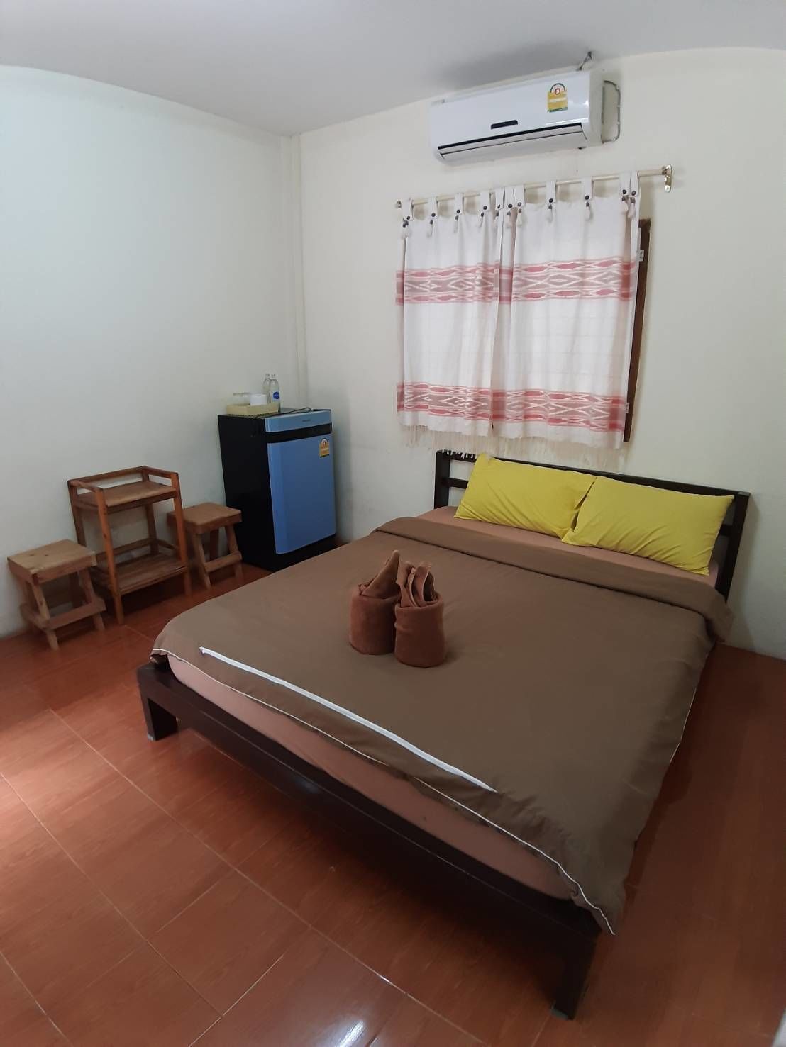 A bedroom with a bed, a desk, a chair, an air conditioner, and a curtain.