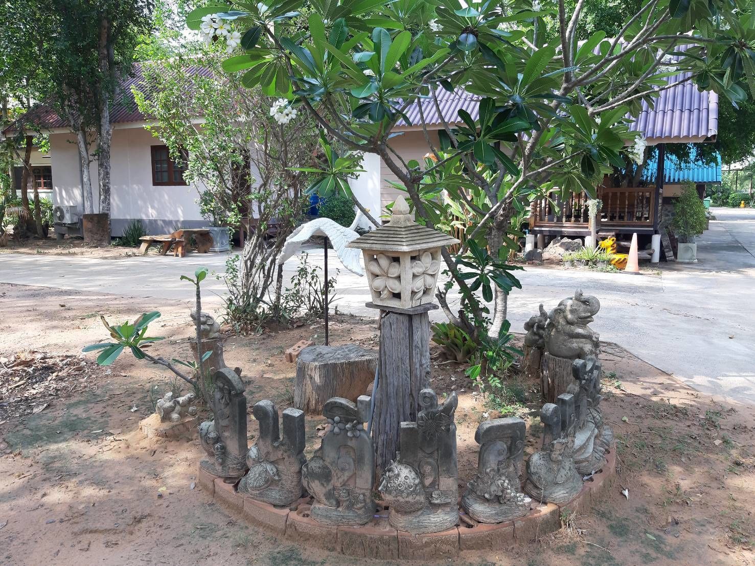 A garden with a stone fountain, surrounded by various plants and trees.
