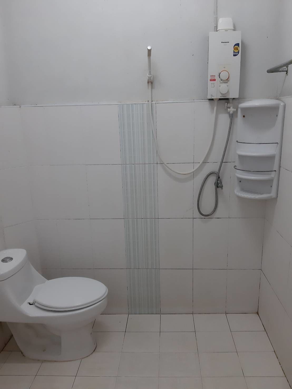 A small, clean bathroom with a toilet, a shower, and a soap dispenser.