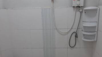 A small, clean bathroom with a toilet, a shower, and a soap dispenser.