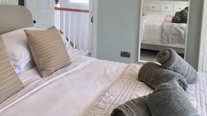 A bedroom with a bed, pillows, a bedside table, a mirror, and a hanging light fixture. - Peaceful and comfortable HOUSE with COUNTRYSIDE views, 5 min drive to beach (Stratton, Bude)