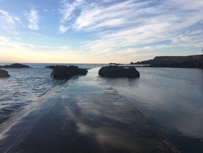 Une promenade en bord de mer avec un sentier en béton menant à des affleurements rocheux.