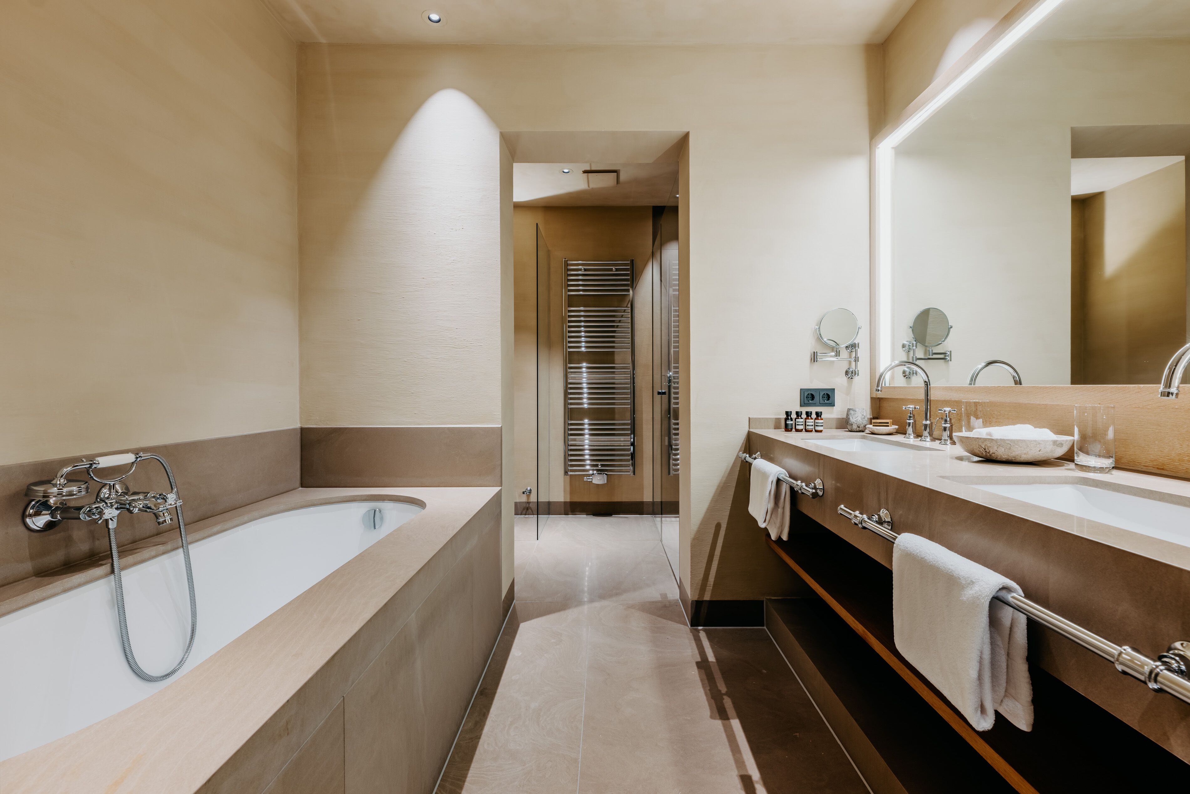 Ein modernes Badezimmer mit einer Badewanne, einem großen Spiegel und einem Waschtisch mit Spüle und Handtuchhalter.