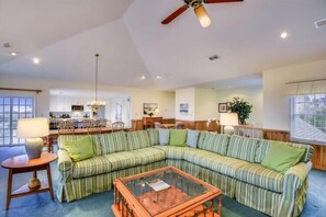 A living room with a sectional sofa, a coffee table, and a dining area in the background. - The Myllet at Ships Watch in Duck (Duck)