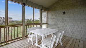 A covered outdoor area with a wooden deck, a white table with chairs, and a brick wall. - The Myllet at Ships Watch in Duck (Duck)