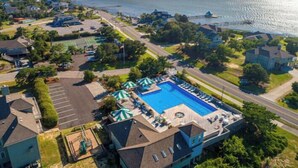 An aerial view of a residential area with a swimming pool, tennis courts, and a waterfront. - The Myllet at Ships Watch in Duck (Duck)