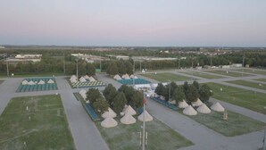 A large, open parking lot with multiple rows of tents and a few buildings in the background. - Festanation Oktoberfest Camp No.1 (Munich)