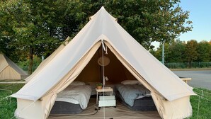 A dome-shaped tent with two beds, a small table, and a hanging light fixture. - Festanation Oktoberfest Camp No.1 (Munich)