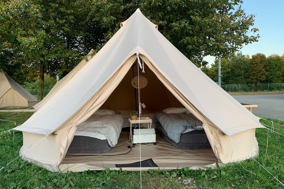 A dome-shaped tent with two beds, a small table, and a hanging light fixture.