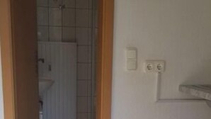 A hallway leading to a bathroom with a tiled floor and a white door. - Monteurwohnungen Viernheim (Viernheim)