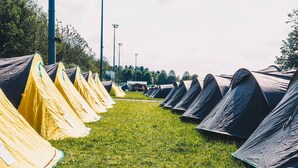 A row of tents on a grassy field with a clear sky. - Festanation Oktoberfest Camp No.2 (Munich)