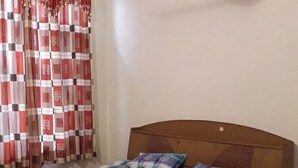 Un dormitorio con cama de madera, ventilador de techo y ventana con cortinas rojas.