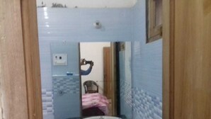 Un baño con un lavamanos blanco, un espejo y una pared con azulejos.