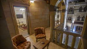 A room with two armchairs, a small table, and a view of a balcony with stone balustrades. - Goreme Reva Hotel (Nevsehir)