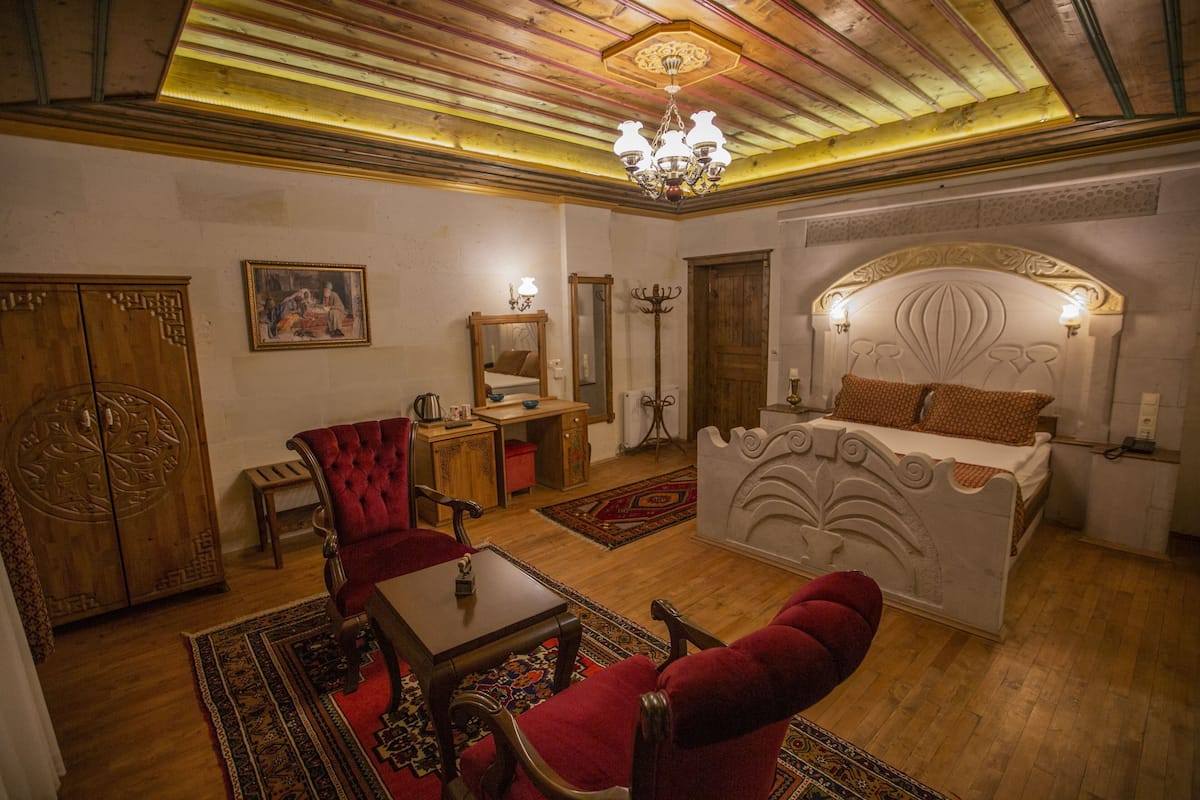 A room with a bed, a red chair, a wooden cabinet, a desk, and a chandelier.
