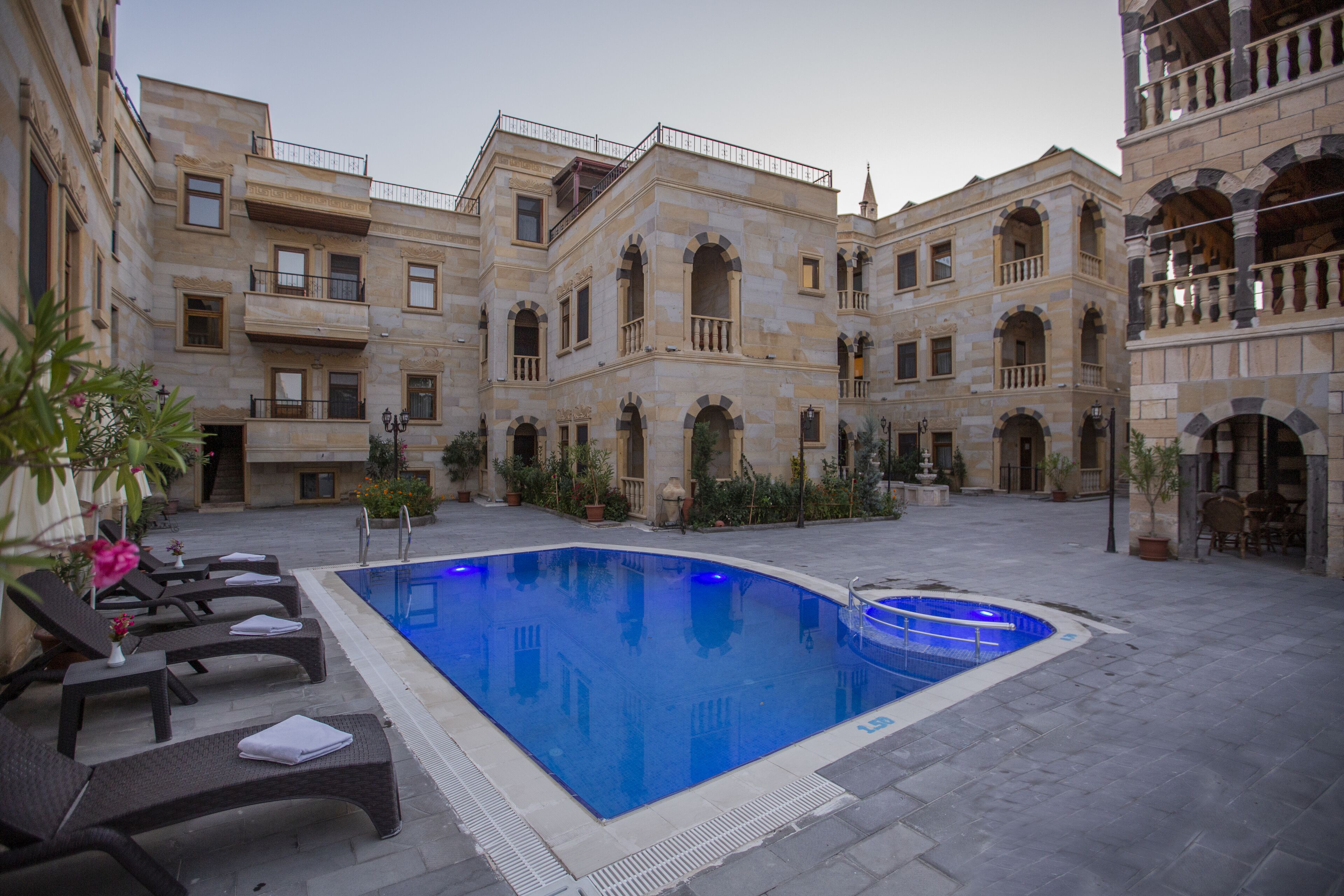 A courtyard with a swimming pool, lounge chairs, and a building with multiple balconies and arches.