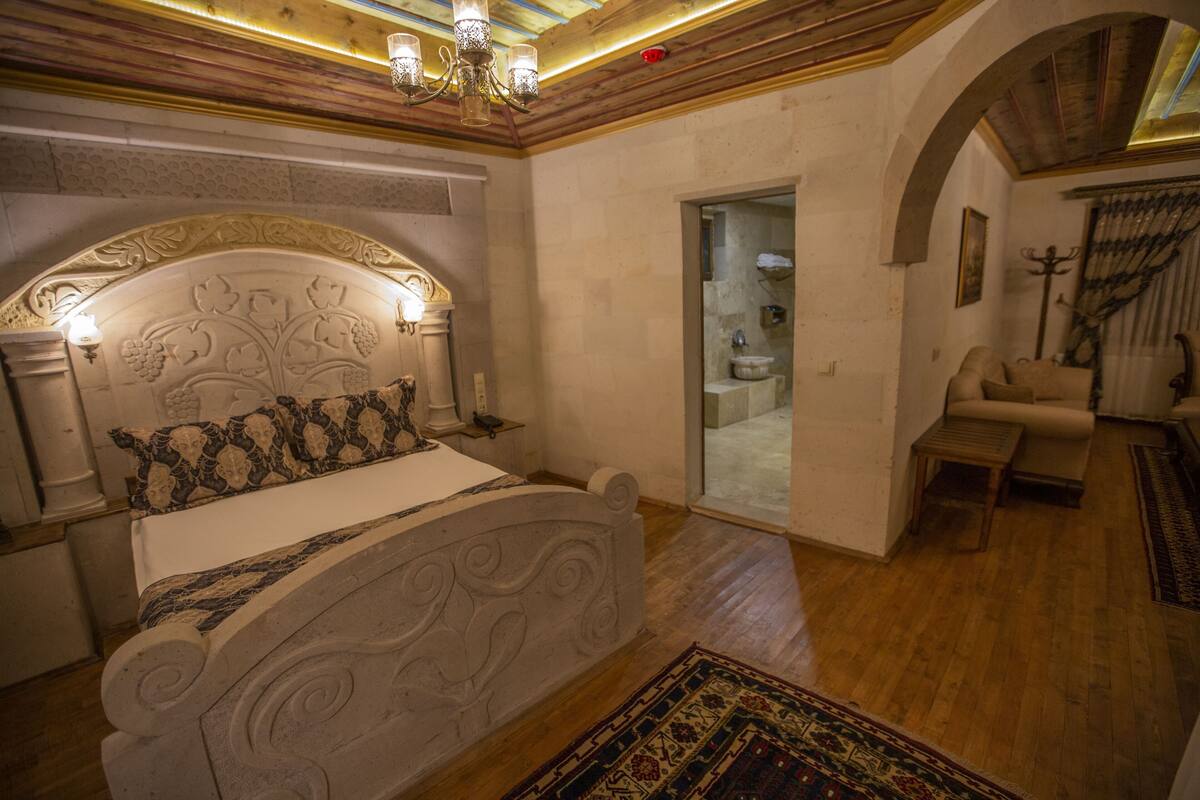 A bedroom with a large bed, a chandelier, and a wooden floor.