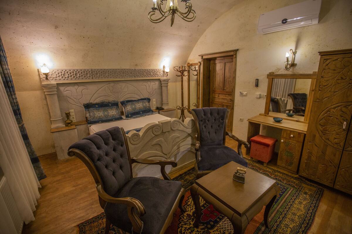 A bedroom with a bed, two armchairs, a small table, a mirror, and a wardrobe.