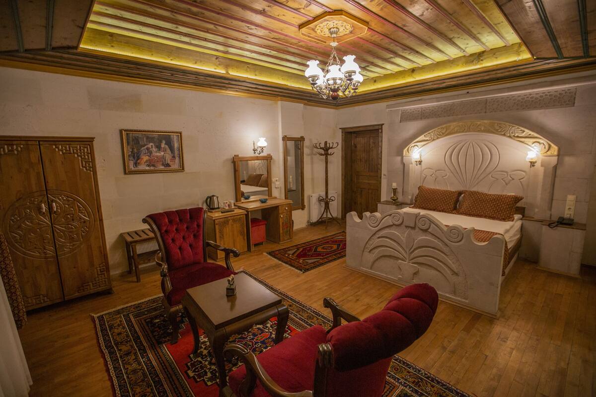 A room with a bed, a red armchair, a wooden cabinet, and a chandelier.