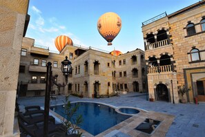 A courtyard with a pool, hot air balloons, and historic buildings.