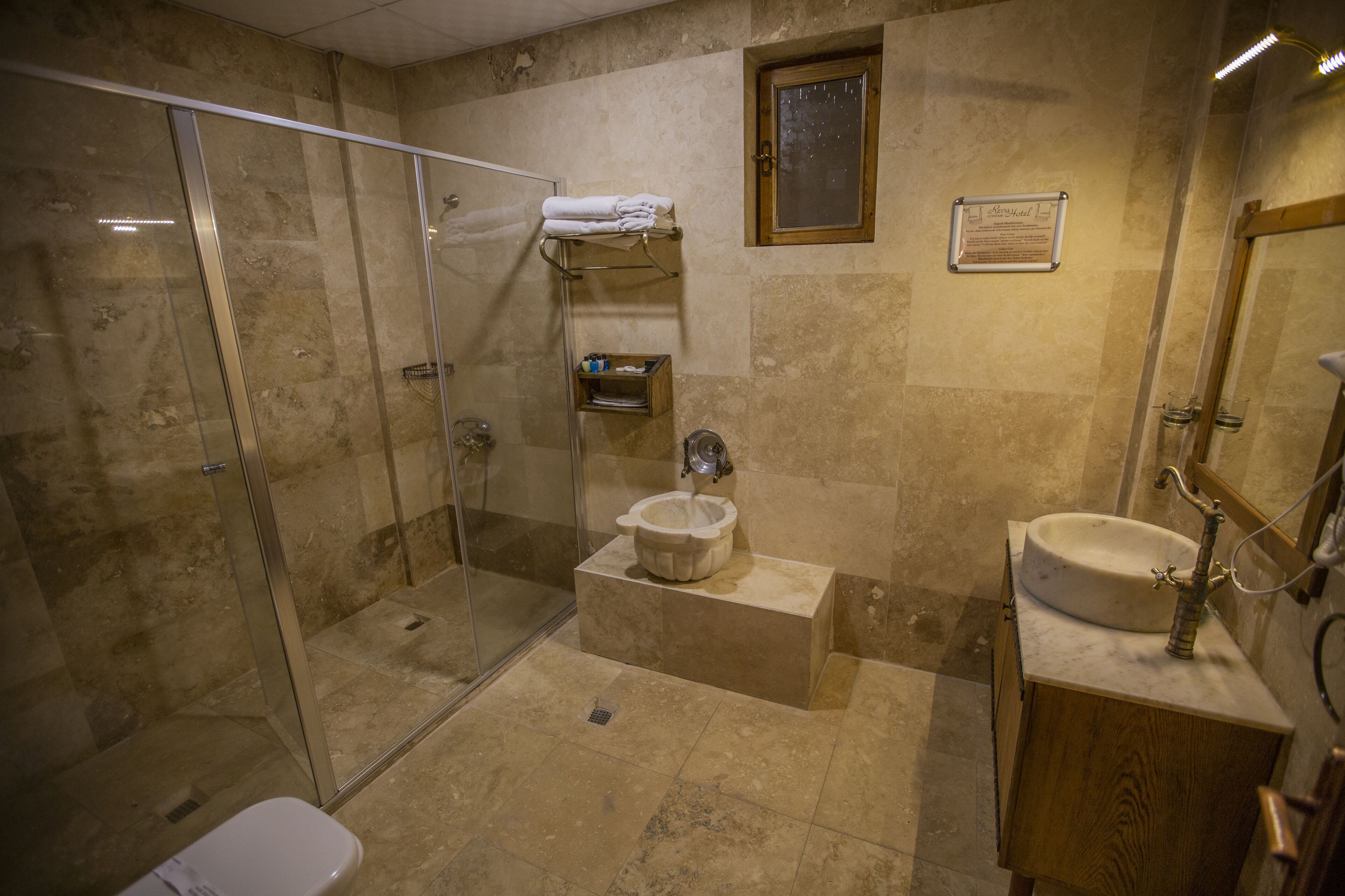 A bathroom with a glass-enclosed shower, a pedestal sink, and a wooden vanity.