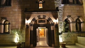 A stone building entrance with an arched doorway, potted plants, and a wooden floor. - Goreme Reva Hotel (Nevsehir)