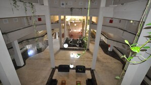 A multi-level atrium with a central open space, columns, and hanging plants.