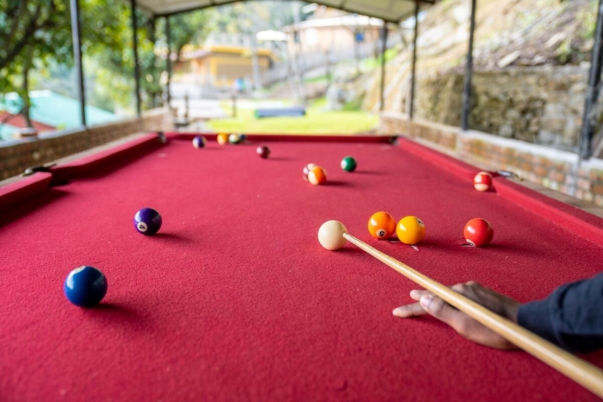 A pool table with balls and a cue stick, indicating a recreational area.