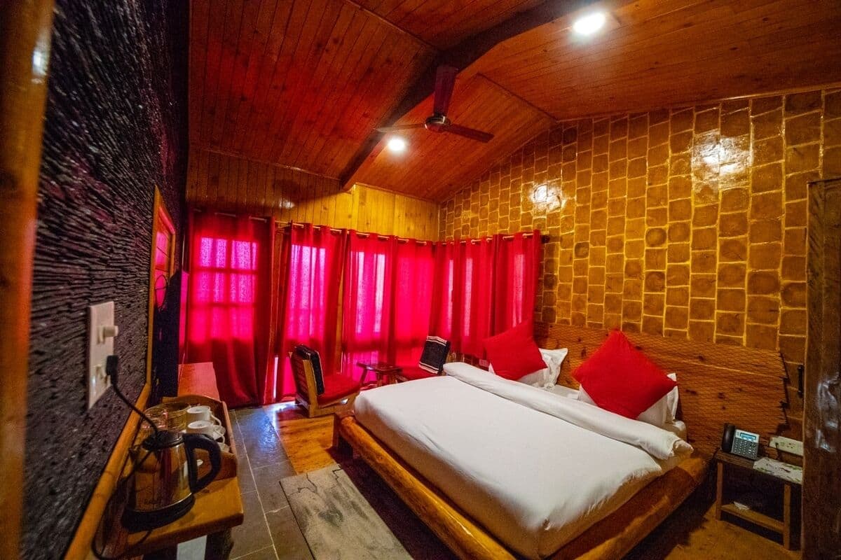 A wooden room with a bed, red curtains, and a wooden ceiling.