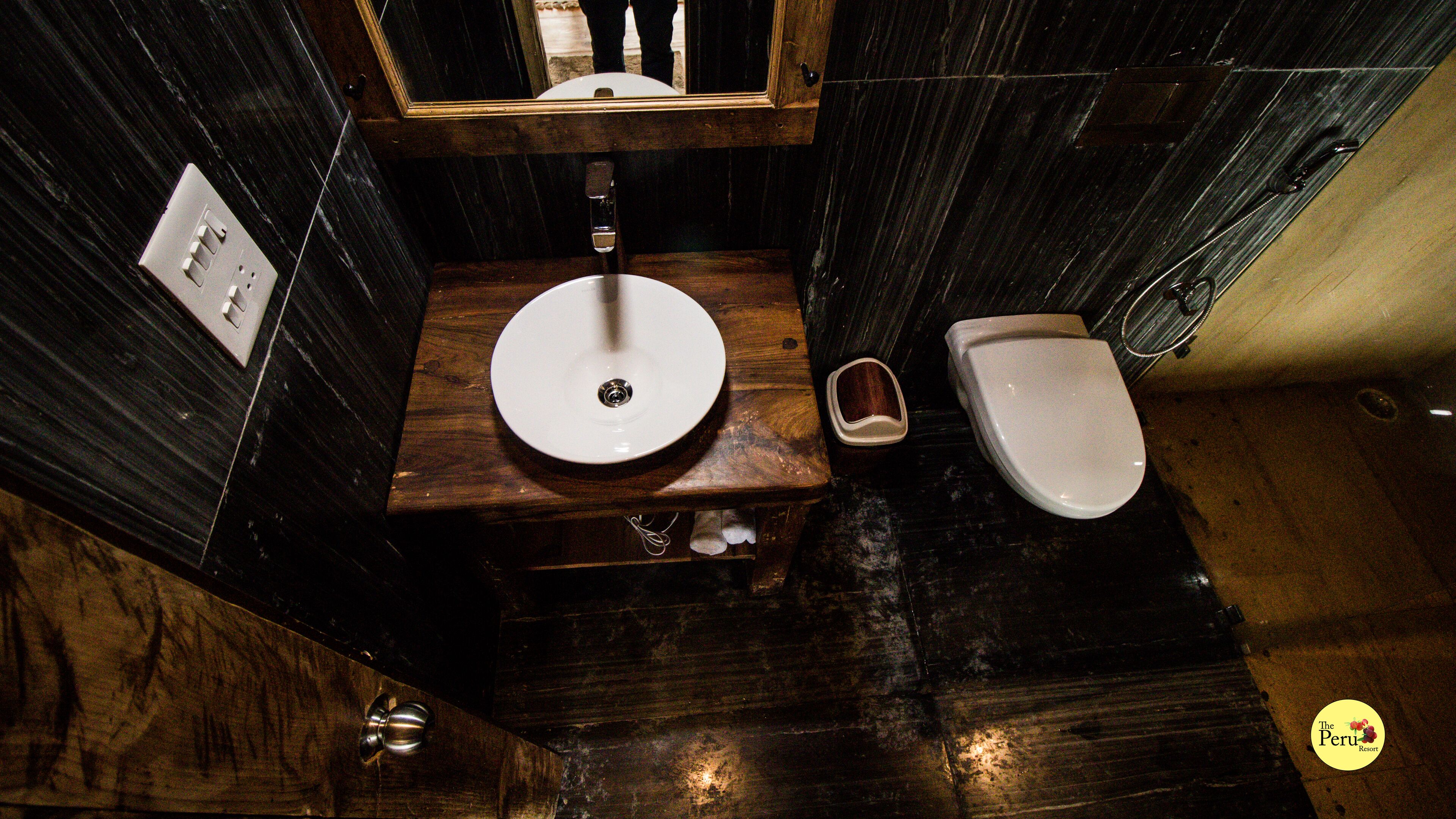 A compact bathroom with a wooden vanity, a sink, and a toilet.
