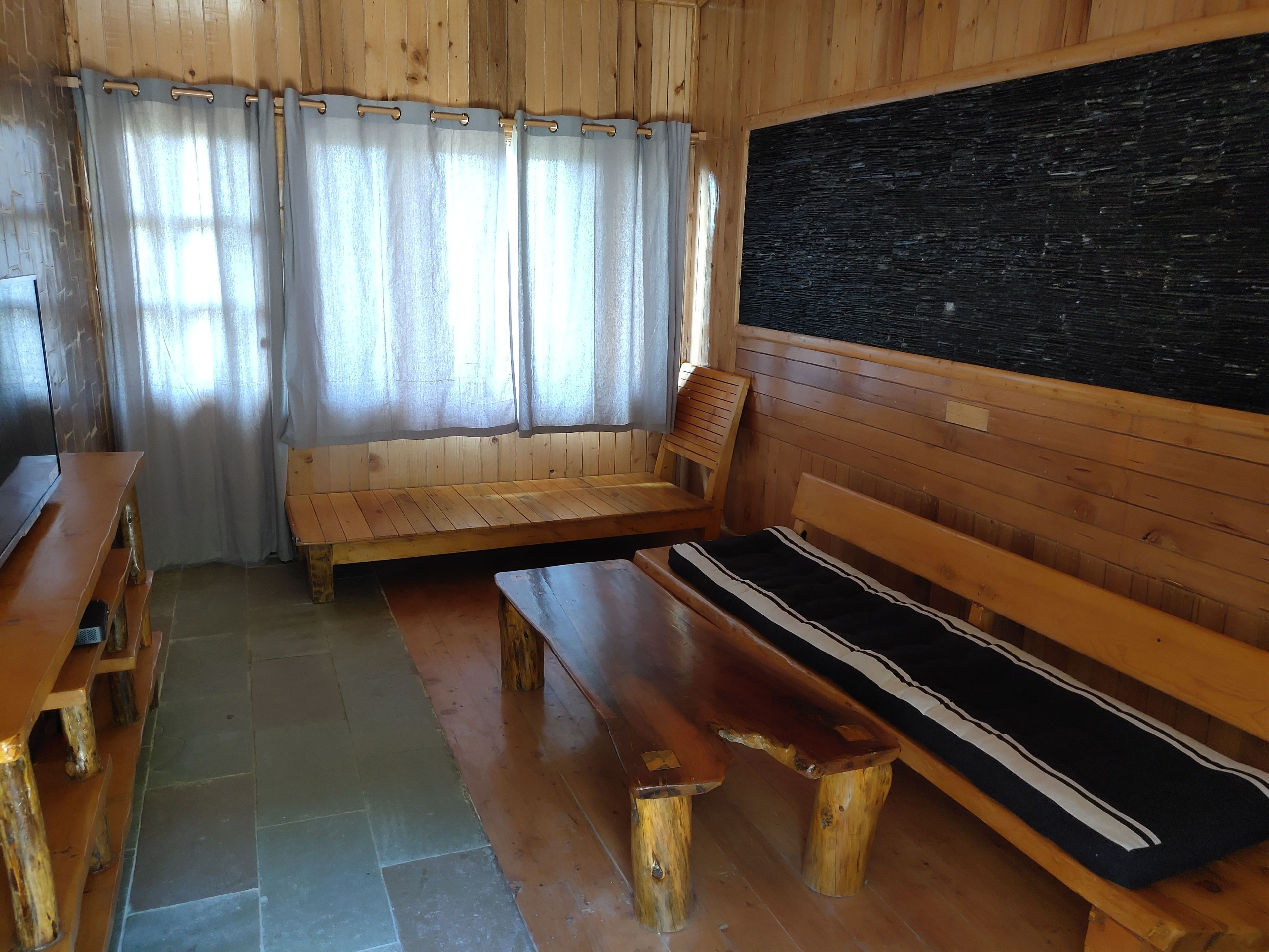 A wooden interior with a bench, a table, and a blackboard.
