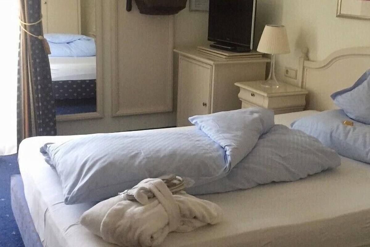 Une chambre d’hôtel comprenant un lit, un téléviseur posé sur un meuble, une table de chevet avec une lampe et une armoire.