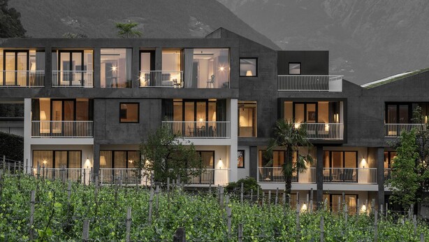 A modern multi-story building with balconies, large windows, and a garden area in front. - Design-Hotel Ballguthof (Lana)