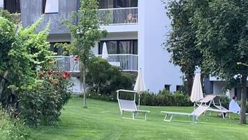 A modern building with a flat roof, multiple balconies, and a well-maintained lawn with outdoor seating.