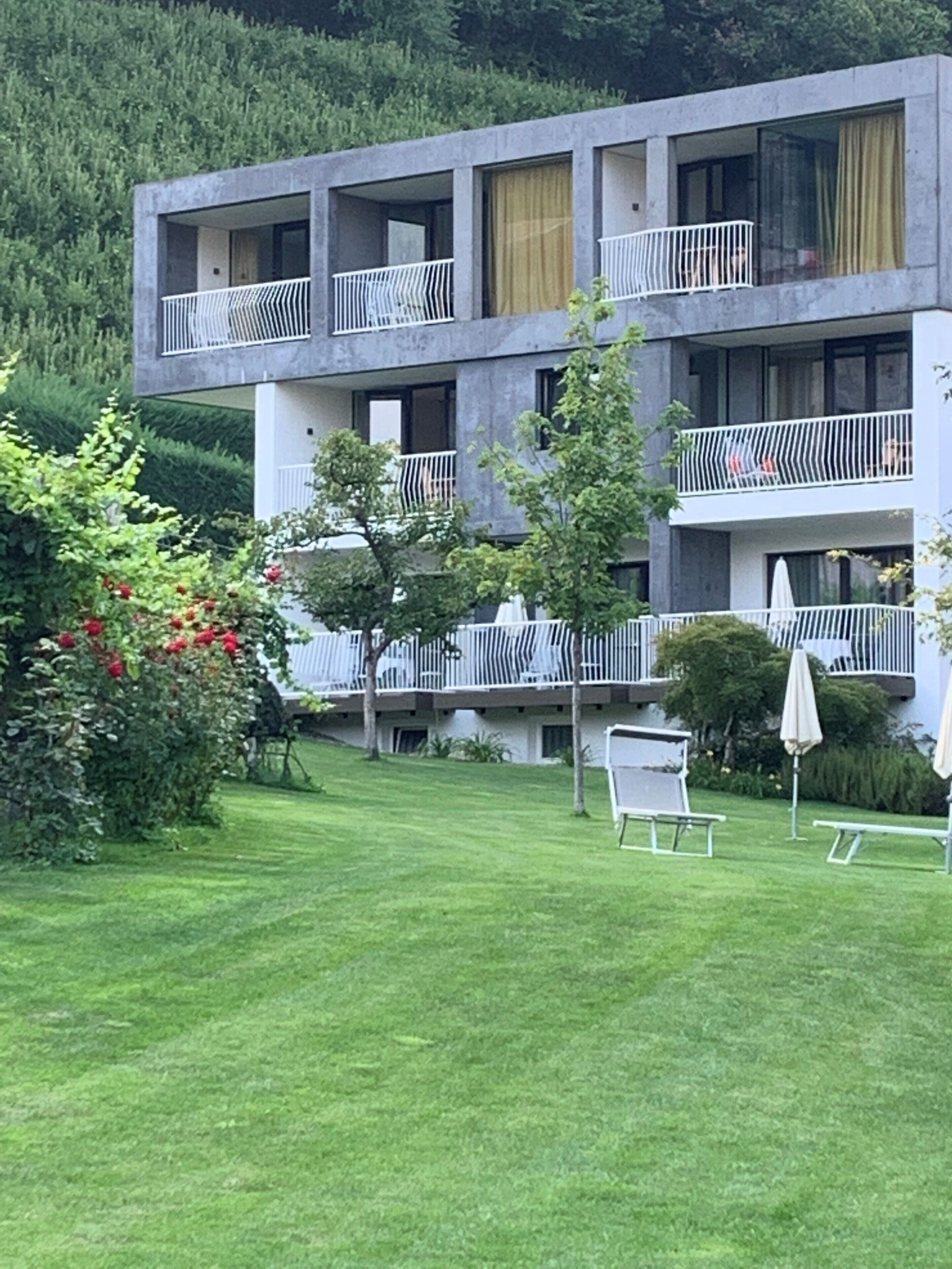 Een modern meerlaags gebouw met balkons, een verzorgd gazon en terrasmeubilair.