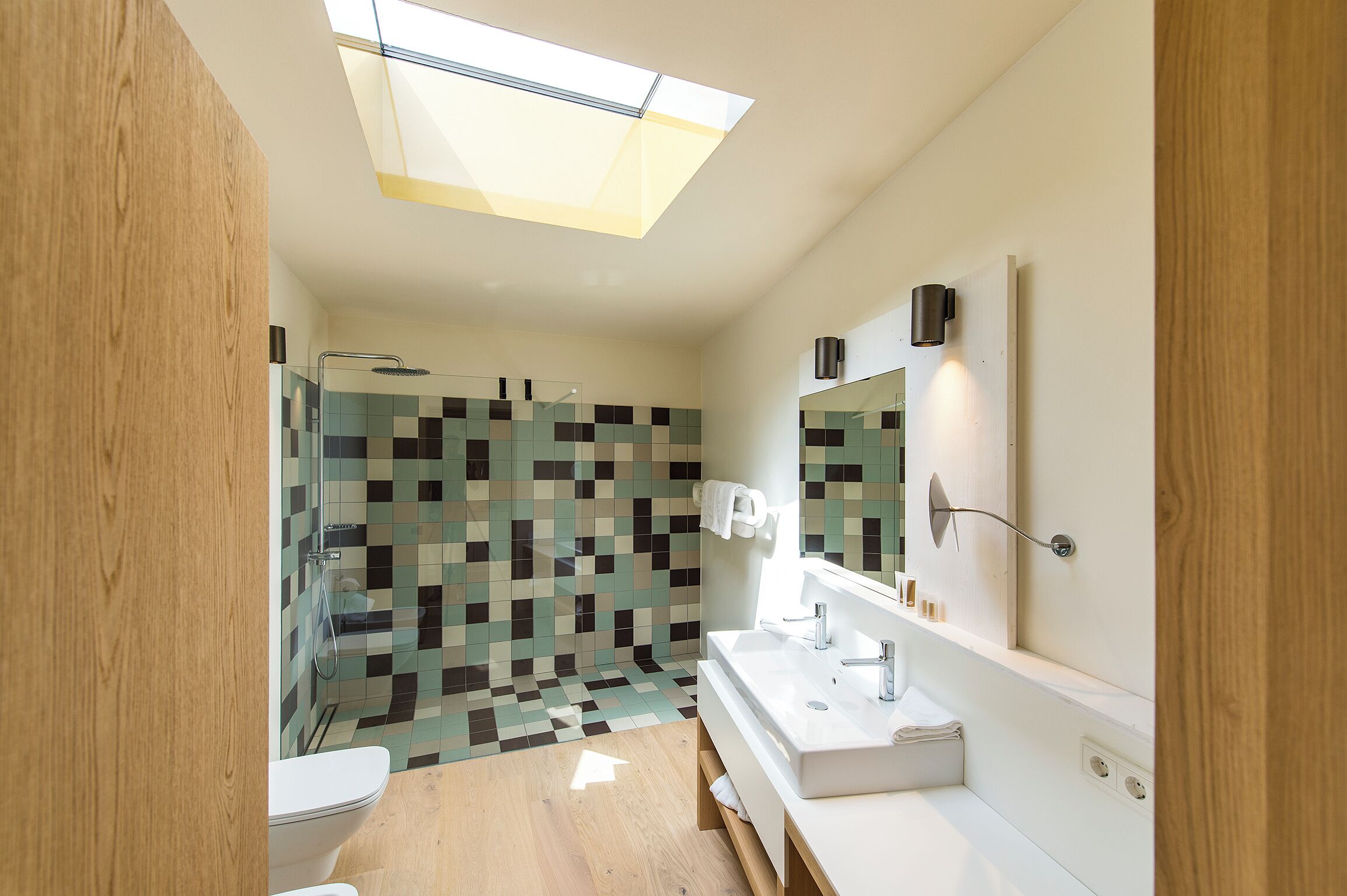 A modern bathroom with a skylight, a shower, and a vanity with a mirror.
