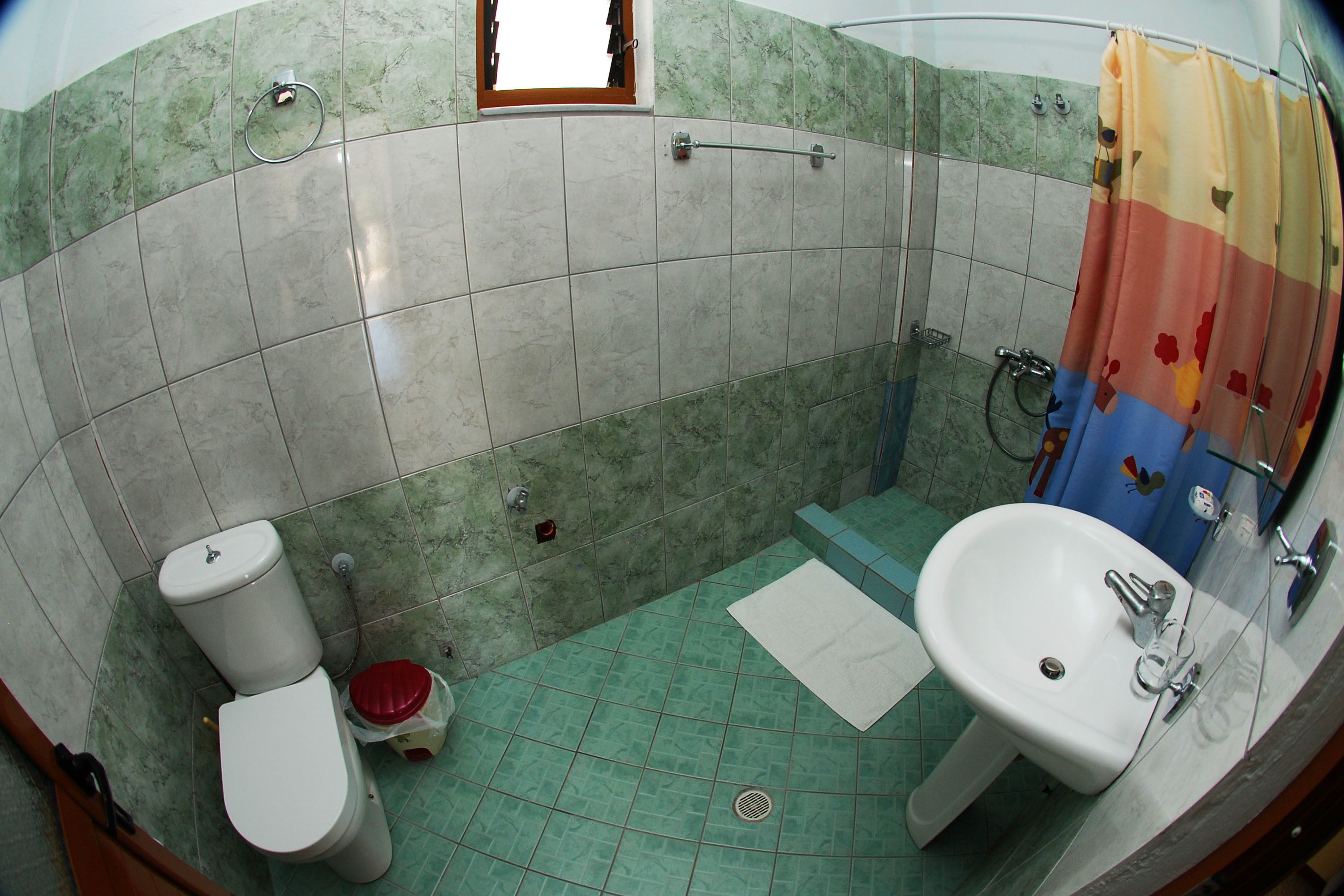 A bathroom with a toilet, sink, and shower area.