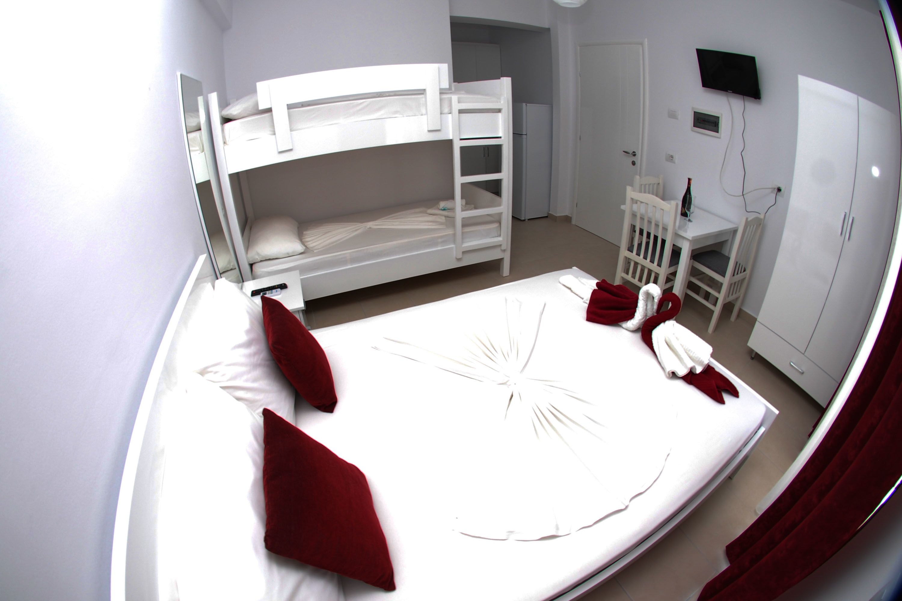 A bunk bed room with a desk and chair, a television, and a wardrobe.
