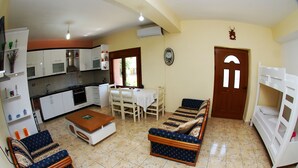 Un espacio habitable compacto con kitchenette, comedor y zona de estar con sofás y una mesa.